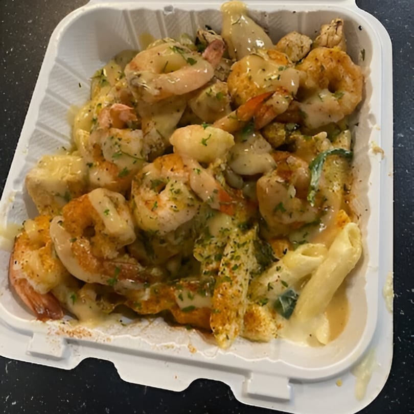 Goldie's Seafood Bar & Grill's shrimp and pasta dish with a creamy sauce and herbs in a takeout container.