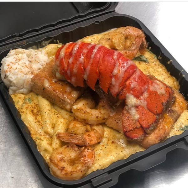Goldie's Seafood Bar & Grill's lobster tail, shrimp, and fish over grits in a to-go container.