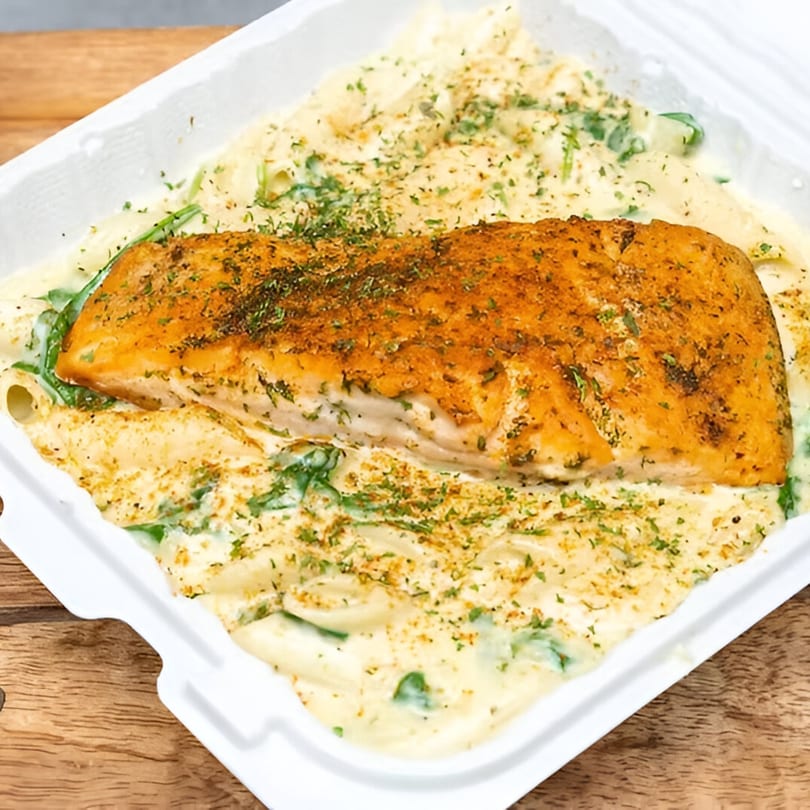 Goldie's Seafood Bar & Grill's salmon with creamy pasta and spinach, topped with herbs.