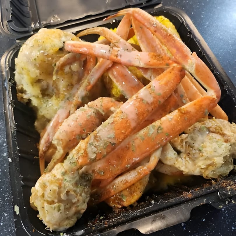 Goldie's Seafood Bar & Grill's snow crab legs and corn on the cob in a black takeout container.